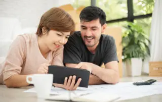 Happy young couple with digital tablet and discussing moving budget.