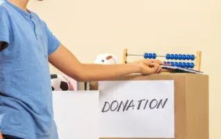 Kid collecting and putting toys, clothes, books, donation goods in donate charity boxes