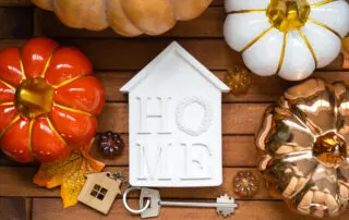 Cozy layout on a wooden background of slats with pumpkins, autumn leaves, a house and keys - autumn mood, Halloween, housing, relocation.