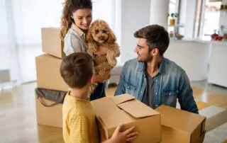 Husband and wife and their son with dog moving in new home. Family, relocation, moving in concept.