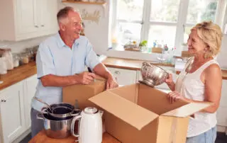 Senior Couple Packing their kitchen And Labelling Boxes Ready For Move Into New Home