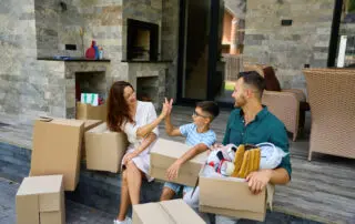 Mother gives high five to her teenage son, father with cardboard moving boxes nearby