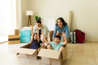 Happy family of four having fun and playing games while moving together into their new house