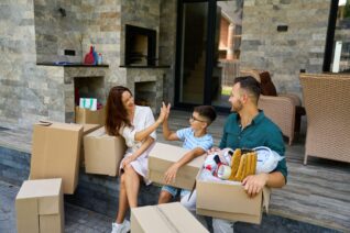 Mother gives high five to her teenage son, father with cardboard moving boxes nearby