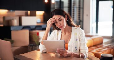 Worry, woman and reading document at new house for property purchase, agreement and hidden fees. Concern, female person and contract with legal terms, lease cost and review information for relocation.