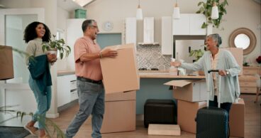 Senior parents, woman and boxes in new home for help, support or luggage with family at property. People, mother and dad with moving, suitcase or excited for investment in real estate for retirement