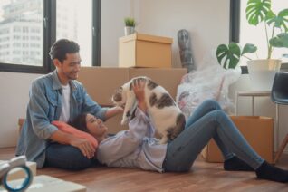Young couple or family feeling happy relaxing and play with their cat after moving to new house or apartment.